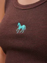 Top de punto acanalado, con diseño ajustado que realza la silueta. Presenta bordados en la parte delantera y trasera, aportando un toque distintivo.