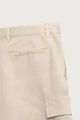 Bermuda cargo regular fit color beige, confeccionada en mezcla de algodón y lino con efecto lavado. Cuenta con bolsillos laterales tipo cargo con solapa en las perneras, bolsillos frontales, cierre frontal con cremallera y botón, y presillas para cinturón.
