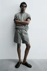 Bermuda de algodón color beige claro, corte relajado (relaxed fit), con cintura elástica ajustable mediante cordón y bolsillos laterales y trasero de plastrón.