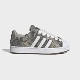Championes Adidas Superstar ST de estilo skate, con exterior estampado en animal print de serpiente en tonos grises y tostados, las icónicas tres tiras blancas en los laterales y la clásica puntera de concha de goma blanca. Cuentan con cordones anchos blancos, lengüeta acolchada y suela chunky blanca con detalles marrones.