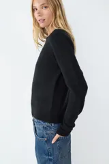 Sweater de manga larga confeccionado en tejido de punto suave, con diseño clásico de cuello redondo y terminaciones acanaladas en puños y bajo.