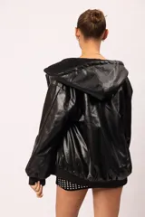 Campera reversible con capucha y cierre metálico frontal. Un lado está confeccionado en eco cuero negro con acabado brillante y el otro en corderito sintético negro. Cuenta con bolsillos laterales decorados con tachas piramidales plateadas, además de puños y cintura de rib elástico.