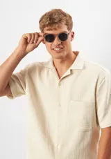 Lentes de sol redondos color champagne con lentes grises. Fabricados con acetato biodegradable y lentes de PMMA reciclado.