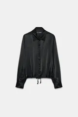 Camisa de satén con cuello solapa, manga larga con puños y bajo ajustable mediante cordones. Presenta cierre frontal con botones ocultos.