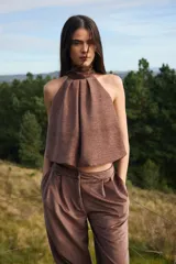 Blusa sin mangas de corte holgado con cuello alto tipo halter y pliegues frontales. Confeccionada en tela con textura sutil.