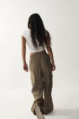 Pantalón cargo de tejido liviano color verde militar, con cintura elástica y cordón ajustable. Presenta diseño de piernas holgadas y bolsillos laterales con solapa.