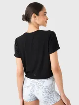 Remera corta negra de tela suave y fresca, con cuello redondo y mangas cortas.