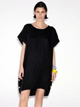 Vestido negro de lino, corte recto, con cuello redondo y mangas cortas. Presenta botones decorativos en la parte inferior.