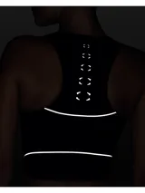 Musculosa deportiva Under Armour de corte crop, color azul marino con detalles reflectantes. Presenta cierre frontal parcial, cuello redondo y perforaciones estratégicas para mayor ventilación.