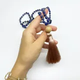 Japa Mala con 108 cuentas de sodalita azul, separadores de hilo color salmón, dije gurú de madera y borla de hilo de seda color beige.