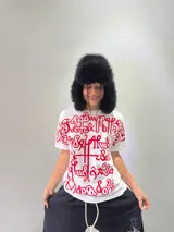 Remera blanca de corte regular con estampado frontal de gran tamaño en color rojo, con diseño de caligrafía abstracta. Confeccionada en algodón de alto gramaje, cuenta con cuello reforzado y grifa de la marca en la manga.