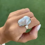 Anillo dorado con una perla irregular blanca.