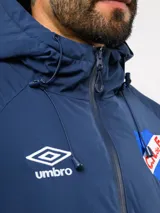 Campera de abrigo Umbro del Club Nacional de Football, con diseño de bloques de color en azul, blanco y rojo. Cuenta con capucha ajustable, cierre frontal y logo de la marca junto al escudo del club en el pecho.