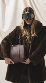 Cartera estructurada de mano color marrón, confeccionada en símil cuero con asas fijas y correa desmontable. Cuenta con bolsillo trasero con cierre, compartimento principal organizado con bolsillos internos y detalle de parche frontal con la marca grabada.