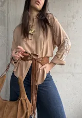 Camisa camel de mangas largas con bordados florales blancos en las mangas, cuello camisero y cierre frontal de botones.