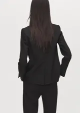 Blazer de corte entallado con solapas de muesca, cierre frontal de un botón, hombros estructurados y mangas largas con puños abotonados. Cuenta con dos bolsillos de ribete delanteros y un bolsillo de ribete en el pecho.