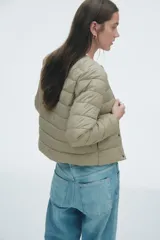 Campera acolchada de nylon con diseño guateado, cuello redondo y cierre frontal mediante botones a presión. Presenta bolsillos laterales discretos, puños con elástico fino y forro interior.