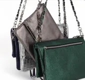 Cartera plateada tipo bandolera con solapa y cierre magnético. Tiene una cadena corta y una cadena larga.