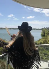 Ruana tejida en lana merino con diseño calado, terminación con flecos largos y caída suave.