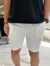 Bermuda deportiva tipo cargo de color blanco, confeccionada en tejido de jogging, con bolsillos laterales con solapa y cintura elástica.
