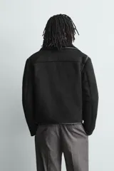 Cazadora cropped fit de tejido efecto piel en color marrón, con interior de borreguillo a tono. Presenta cuello solapa, cierre frontal con botones, bolsillos de plastrón en el pecho y bolsillos de vivo en la cadera.
