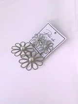 Aros colgantes plateados en forma de flor con perla en el centro, compuestos por dos margaritas unidas en cascada.