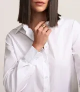 Camisa básica de mujer confeccionada en tricolina de algodón, con cuello solapa, cierre frontal de botones y mangas largas con puños abotonados.