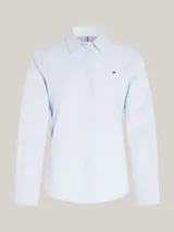Camisa celeste de popelín de algodón orgánico, corte regular, cuello inglés, puños con botón, bajo redondeado y logo de Tommy Hilfiger bordado en el pecho.
