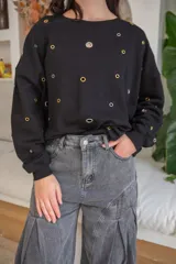 Sweater negro de algodón con corte holgado y cuello redondo. Decorado con ojales metálicos dorados y plateados.