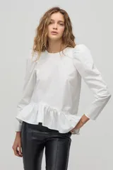 Blusa blanca de algodón con mangas largas abullonadas y peplum asimétrico con volantes.