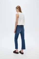 Pantalón jean de corte recto y tiro alto, en color azul, con diseño clásico de cinco bolsillos y terminación desmechada en los tobillos.