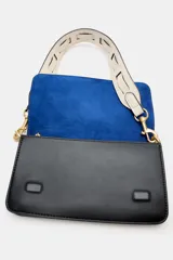 Bolso bandolera rectangular de color negro con solapa y cierre de botón imantado, herrajes metálicos dorados y compartimento interior con cremallera. Incluye una correa ancha ajustable y extraíble en combinación de colores azul y blanco.