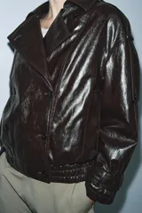 Chaqueta de efecto cuero con acabado brillante, cuello de solapa con aplicación de pelo sintético extraíble, cierre frontal cruzado con botones, mangas largas con puños ajustables y bajo elástico. Cuenta con forro interior acolchado.