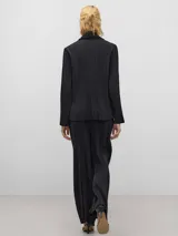 Pantalón negro con textura arrugada, corte holgado y cierre con botón.