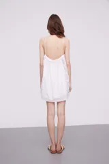 Vestido corto color marfil con breteles finos, escote recto y detalle de puntilla en los laterales y ruedo.