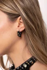 Aro tipo argolla pequeña de acero quirúrgico, decorado con mostacillas negras y doradas entrelazadas alrededor de toda la estructura.