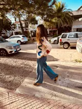 Sweater color crema con bordados geométricos en azul, verde, rojo y marrón. Tiene cuello redondo y mangas largas. Corte holgado.