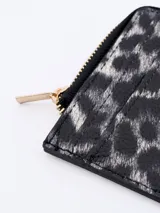 Billetera pequeña con estampado animal print en tonos grises y negros, cierre superior con cremallera dorada y ranuras para tarjetas.