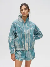 Short de estilo deportivo con pretina elástica, confeccionado en tela satinada con estampado tipo tie-dye en tonos azul y blanco. Presenta bordes con vivo en color crema y un pequeño logo bordado en la parte inferior.