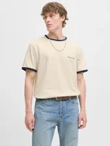 Remera de manga corta color beige, de corte relajado, con cuello redondo y ribetes en contraste de color azul marino en el cuello y los puños. Presenta un pequeño bordado en el pecho.