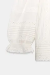 Blusa blanca de manga corta abullonada con puño elástico, escote cuadrado y detalles de puntillas y pinzas verticales en el frente.