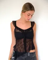Top de encaje negro con breteles anchos y diseño asimétrico en el ruedo. Presenta un estilo romántico con volados sutiles en los bordes y una estructura que simula un corset.