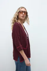 Kimono de tejido de punto color bordó, de diseño abierto con mangas tres cuartos y bolsillos frontales con detalles en rojo.