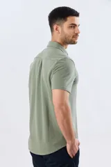 Camisa de piqué lisa color celeste, de manga corta, con cuello camisero y cierre frontal de botones oscuros.