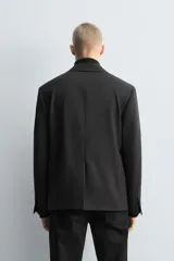Blazer de corte relajado confeccionada en mezcla de lana y viscosa. Presenta cuello con solapas de muesca, cierre frontal de un botón, bolsillos con solapa en la cadera y abertura central en la espalda. Incluye forro interior a contraste y puños con botones.