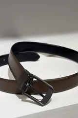 Cinto reversible para hombre, con una cara negra y otra color chocolate, fabricado en cuero con hebilla metálica de diseño clásico.