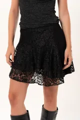 Pollera corta de encaje negro con diseño de vuelos y movimiento ligero, ideal para un look romántico y elegante.