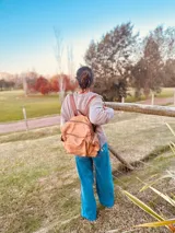 Mochila marrón de cuero con efecto gastado, múltiples bolsillos con cierre y correas ajustables.