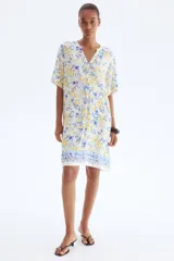 Vestido túnica a la rodilla en tejido liviano de viscosa con cuello mao y abertura en V. Modelo de corte holgado con hombros levemente caídos, mangas cortas y bajo recto con tajos laterales. Parte posterior algo más larga. Estampado de limones y flores azules.