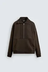 Sudadera de corte relajado color marrón oscuro, con cuello subido y cierre frontal de cremallera. Presenta manga larga, bolsillo frontal tipo canguro y acabados en rib en puños y ruedo.